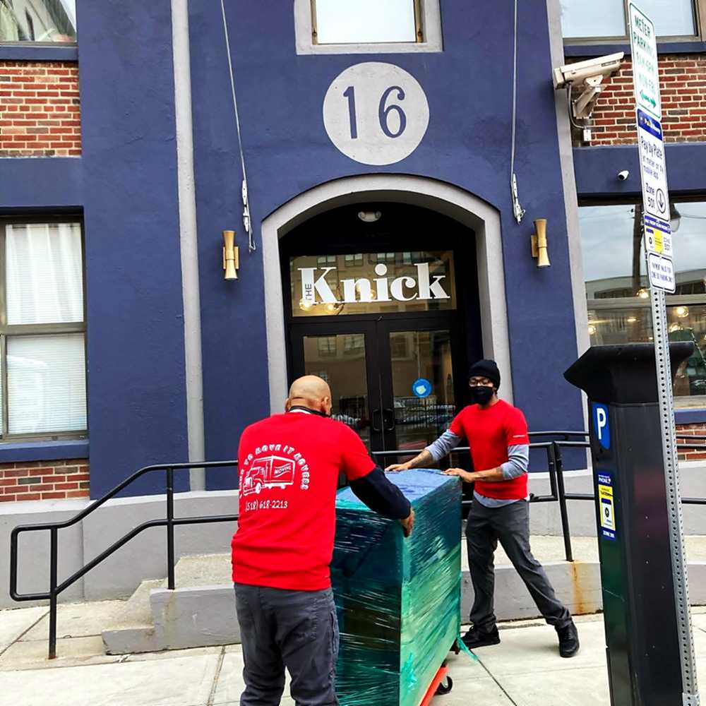 Two I Like To Move It crew members wheeling a packed bin to the truck