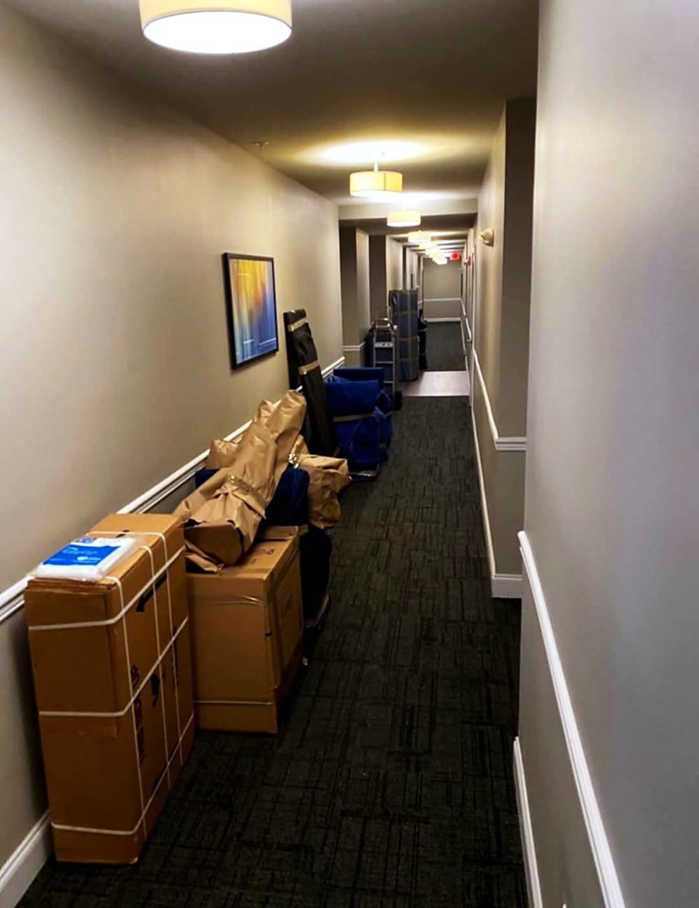 Boxes and wrapped furniture staged along an apartment corridor